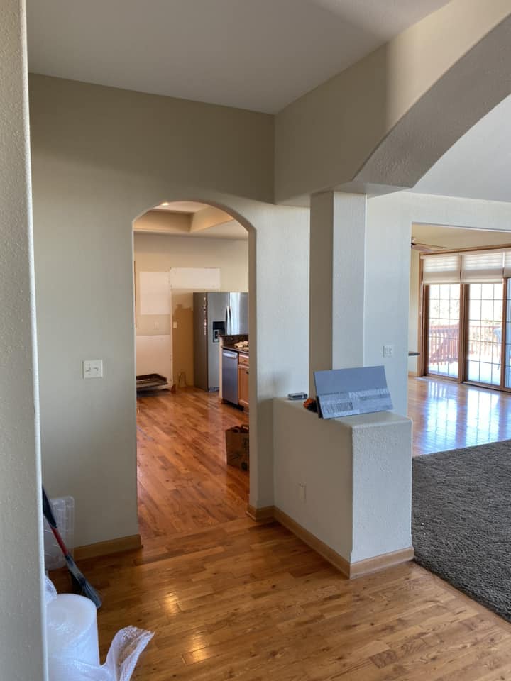 Existing interior hallway view through arched opening toward kitchen and living area during renovation prep